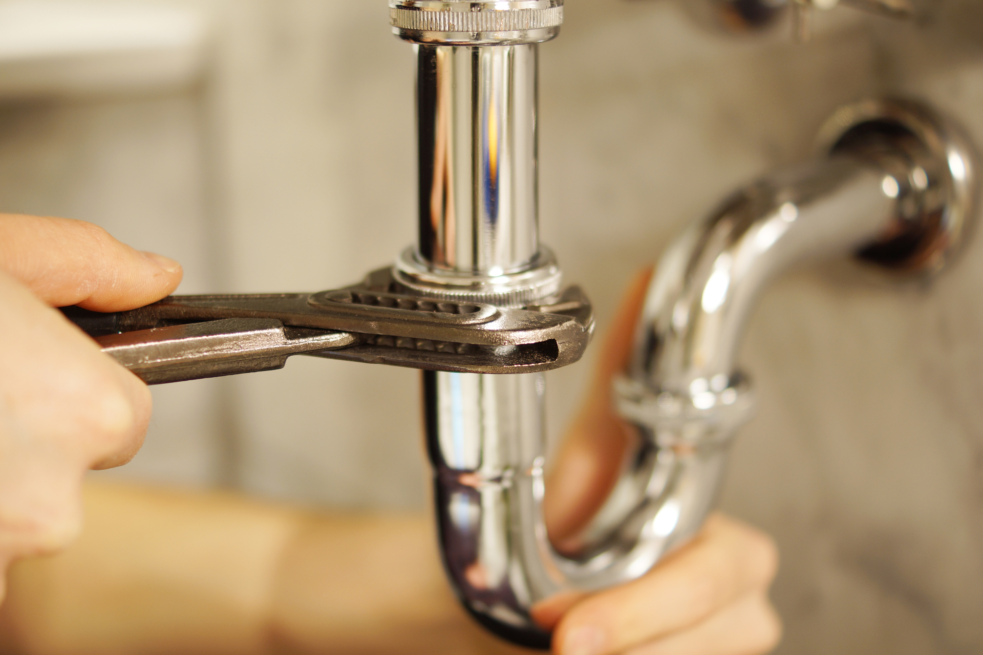 Hands tightening a sink drain with a wrench